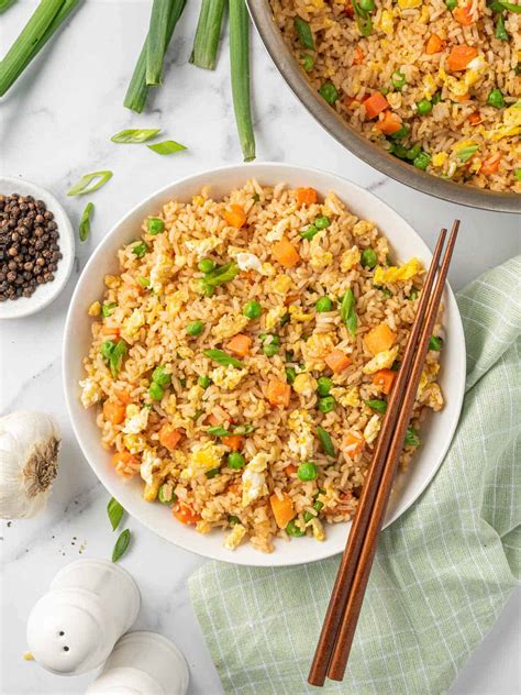 Thematic photo of a bowl of freshly prepared Chinese fried rice with vegetables and chopsticks