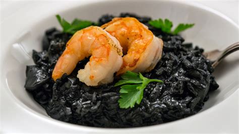 Servirana veganska črna rižota z veganskim parmezanom