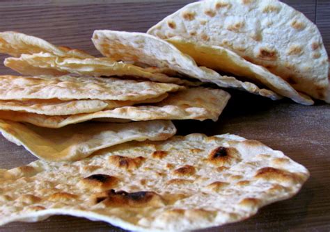 Fotografija razvaljanega testa za mlinci na pomokani površini.