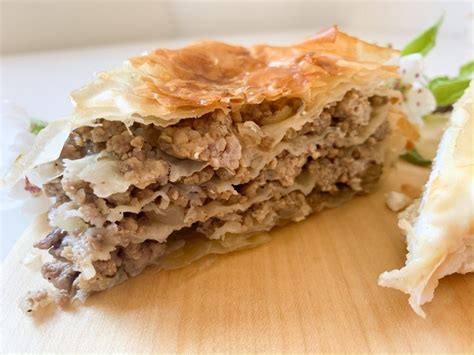 Mesni burek iz vlečenega testa na leseni podlagi