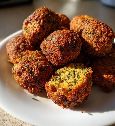 Photo of crispy falafel balls in a bowl, garnished with fresh herbs.