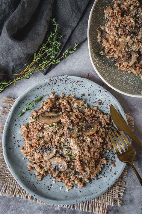 A creamy buckwheat risotto with mushrooms and spinach, garnished with fresh herbs