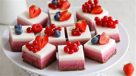 Pripravljene jogurtove rezine z gozdnimi sadeži, narezane na kocke, z vidnimi sloji kreme in sadja.