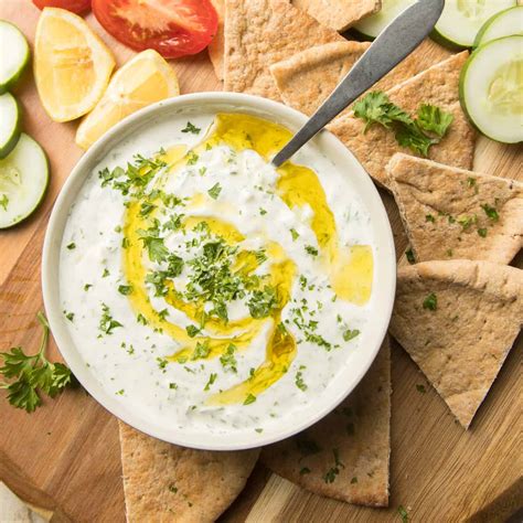 Pripravljen tzatziki v skledi, okrašen z oljko in zelišči.