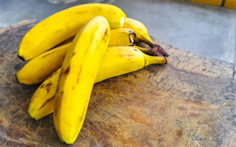 slika zrele banane in pomaranče na leseni deski