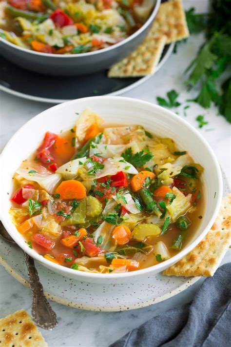 Thematic photo of a bowl of cabbage soup with fresh ingredients in the background.