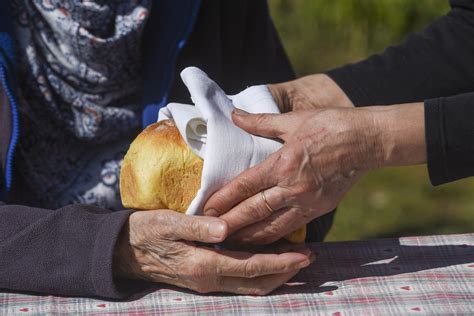 Tematska fotografija roke, ki spoštljivo pobira kruh s tal