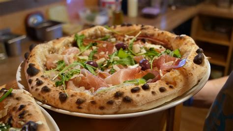 fotografija sveže pečene napolitanske pizze z bogatimi sestavinami v ambientu restavracije