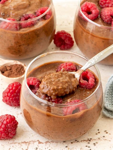 Thematic photo of a healthy chocolate pudding in a glass bowl, garnished with berries, next to konjac flour. Focus on the pudding with a slightly blurred background of ingredients.