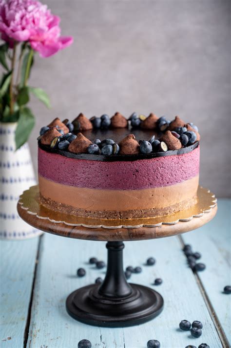 slika tortnega reza, ki prikazuje plasti: hrustljavo piškotno dno, svetlo malinovo plast in temno čokoladno kremo