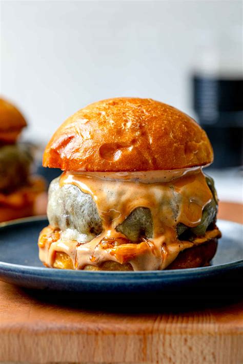 Sestavljen goveji burger s svežimi dodatki in obilico omake
