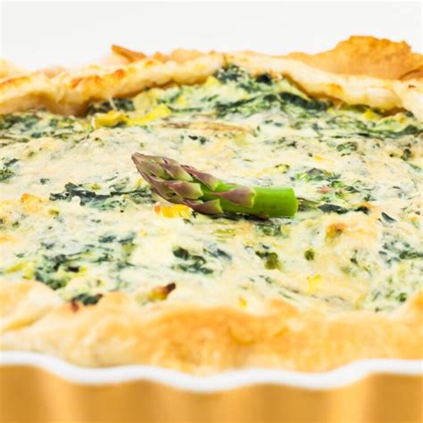 Fotografija sveže pečene pite s šparglji, gobami in porom na rustikalni mizi