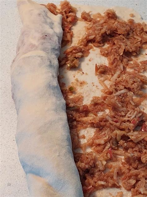 Pripravljen jabolčni zavitek pred peko, premazan z maslom