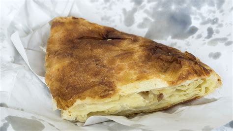 Fotografija sveže pečenega, hrustljavega bureka na pladnju v pekarni.