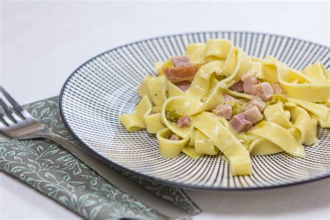 Zbirka različnih omak s šunko za testenine, predstavljenih v skodelicah.