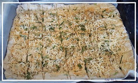 Surovo testo za upognjence na pekaču, posuto z janeževimi semeni, pred peko