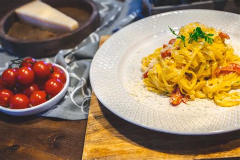 Fotografija servirane fižolove mineštre, posute s parmezanom in svežimi zelišči