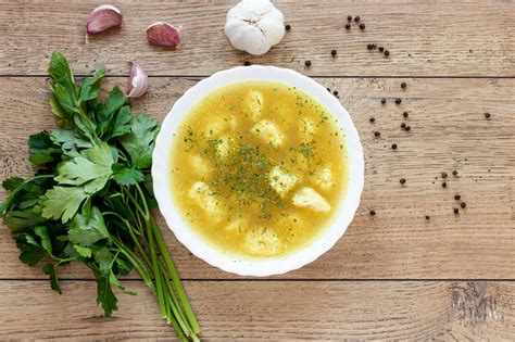 Prikaz sestavin za kostno juho: telečje kosti, sveža jušna zelenjava, jabolčni kis in začimbe