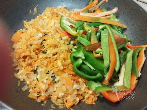 Ilustracija sveže paprike, narezane na trakove, s čebulo in česnom v ponvi.