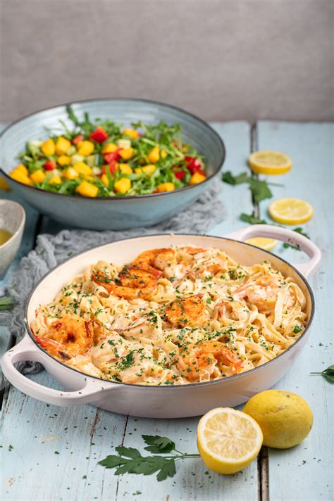 Pripravljena jed: testenine v kremni omaki iz paprike, okrašene s svežo baziliko.