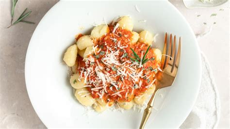 Pripravljeni njoki s kremno omako iz praženih paprik, okrašeni z dodatki.