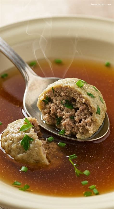 A plate of freshly prepared liver dumplings in a clear beef broth with chopped parsley.
