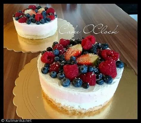Fotografija visoke, večplastne biskvitne torte, okrašene s svežim jagodičevjem in smetano.