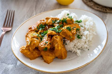krožnik z aromatičnim piščancem v rumeni curry omaki z basmati rižem in svežim koriandrom