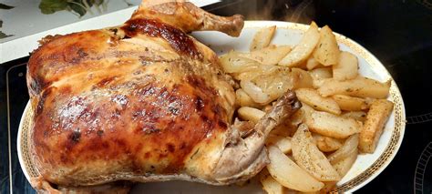 Pripravljen nadevan piščanec v pečici, postrežen s prilogo.