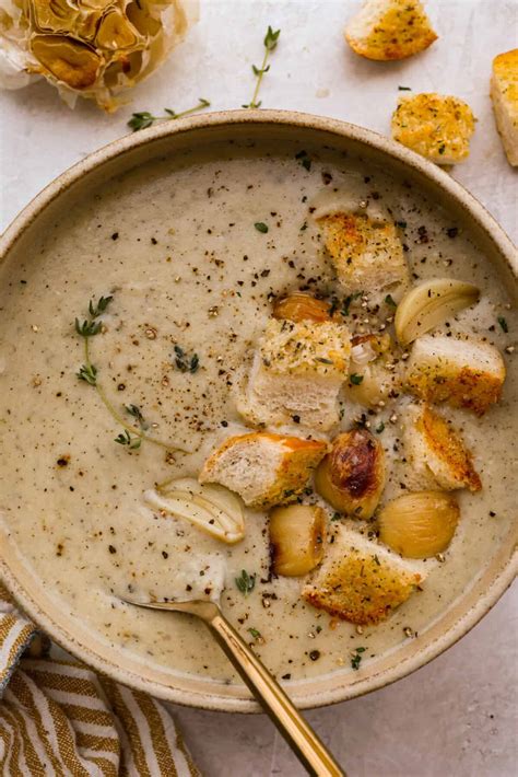Thematic photo of a bowl of creamy garlic soup with croutons.