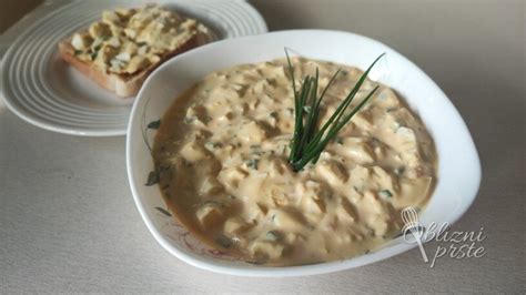Fotografija krožnika s segedinom, postreženim s kislo smetano in kosom kruha.