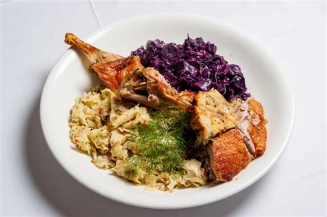 Ilustracija praznične mize z gosko, mlinci in rdečim zeljem.