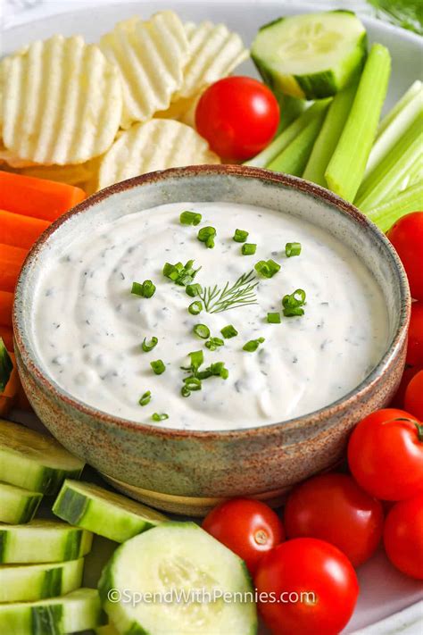 A bowl of creamy ranch dip surrounded by fresh herbs