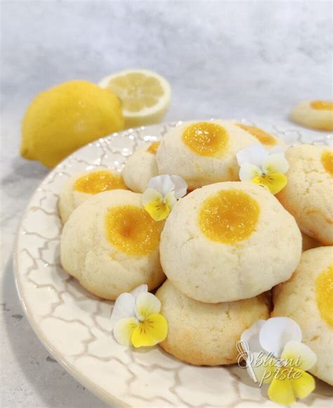 Prikaz pripravljenih maslenih piškotov, okrašenih z limoninim ledom in drugimi dodatki.