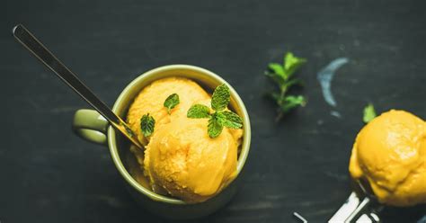 Mangov sorbet v skodelici, okrašen z lističi mete