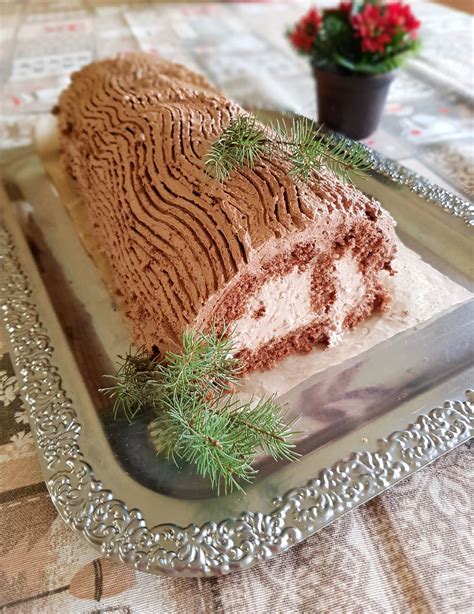 Fotografija estetsko postrežene čokoladne božične rolade na prazničnem krožniku z dekoracijo iz brusnic