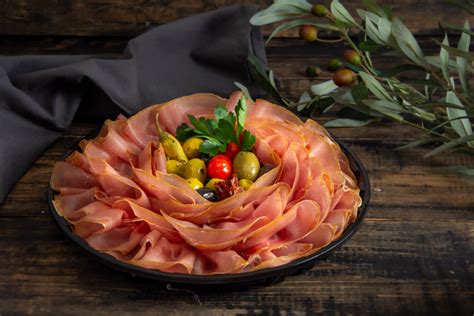 Pladenj s kraškim pršutom, sirom, olivami in grozdjem ter kozarci vina