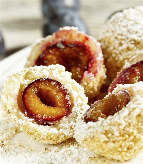 Ilustracija kvašenih cmokov, polnjeni s slivovo marmelado, potreseni s sladkorjem v prahu in makom, ob strani pa vaniljeva omaka.