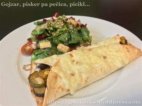 Pripravljene, pečene piščančje tortilje s polnim nadevom in posipom sira, pripravljene za serviranje.