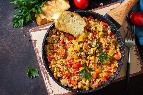 Tapenada servirana v skodelici, obdana s svežim kruhom, olivami in sirom.