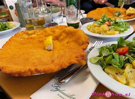 Ikonični dunajski zrezek (Wiener Schnitzel) na krožniku, obdan s prilogami.