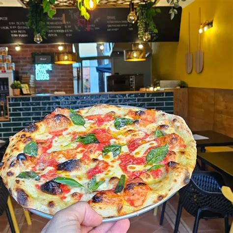 Fotografija moderne picerije Pop's Pizza v Ljubljani, z ljudmi, ki uživajo v picah
