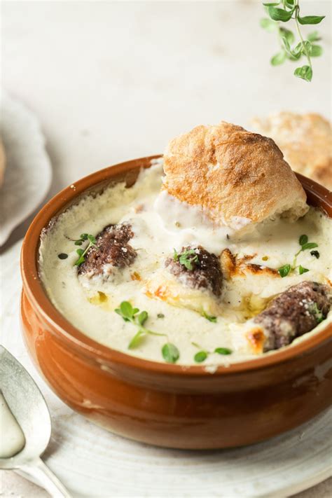 fotografija tradicionalne štajerske kisle juhe v glineni posodi, postrežene z zelišči