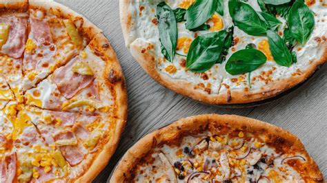 Pripravljena pica z raznolikimi zelenjavnimi dodatki in sirom, pripravljena za peko.