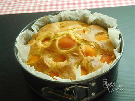 Sveže narezane marelice na vrhu puhastega biskvitnega testa