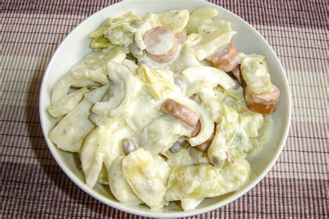 Fotografija sveže pripravljene krompirjeve solate s hrenovko na piknik mizi