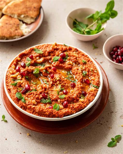 Thematic photo of Muhammara spread with pita bread and vegetables.