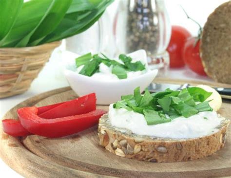 Slika sklede kremastega skutnega namaza s svežimi zelišči.