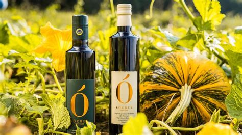 Temnozeleno bučno olje v steklenici, obkroženo z bučnimi semeni