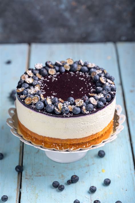 Prikaz končne borovničeve torte, okrašene s svežimi borovnicami in smetano.